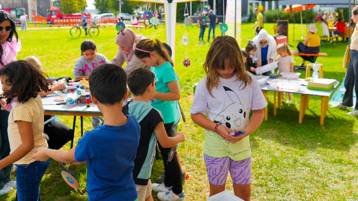 Kinder und Erwachsene auf einer Wiese unter einem Pavillon.