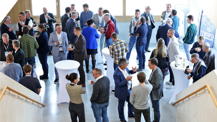 Beim Energieforum der Innovationsregion Ulm e. V. unterhalten sich die Besuchenden im Eingangsbereich an Stehtischen.
