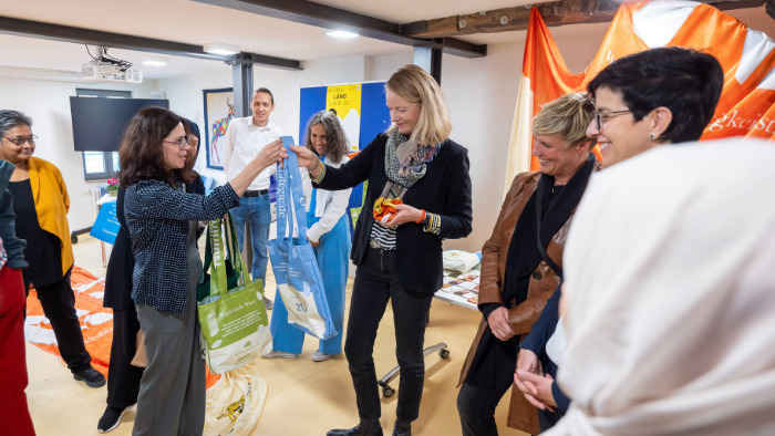 Die Integrationsbeauftragte der Stadt Metzingen Karina Montes übergibt der Umweltministerin Thekla Walker eine Tasche aus recycelten Stoffen der Nachhaltigkeitsstrategie Baden-Württemberg.