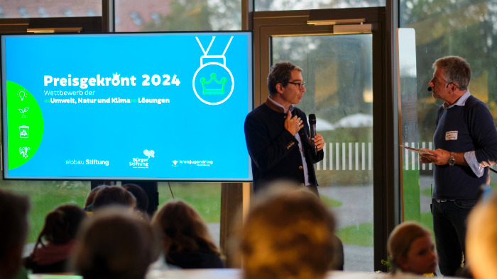 Dr. André Baumann spricht vor den Menschen zum Finale des Wettbewerbs "Preisgekrönt".