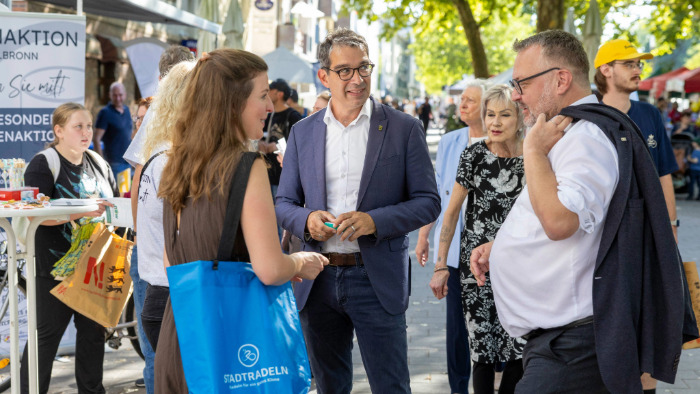 Staatssekretär Andre Baumann spricht mit Menschen an den Ständen des Nachhaltigkeits- und Mobilitätstag der Stadt Heilbronn.